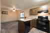 a kitchen with black appliances and dining room with a window in the background Newgate Apartments |Bismarck, ND