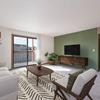 Garden Grove | Mandan, ND  - A living room with a couch, chair, television, coffee table, glass sliding door, and a green wall 