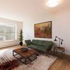 a living room with a green couch, large wall art, and large window in a studio apartment Norma | Bismarck, ND