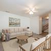  Bismarck Pebble Creek Apartments. The spacious living room is tastefully decorated with stylish furniture, ample natural light, and a cozy atmosphere. There's overhead lighting with a touch of natural light from the dining room. Access to the upstairs is in the background